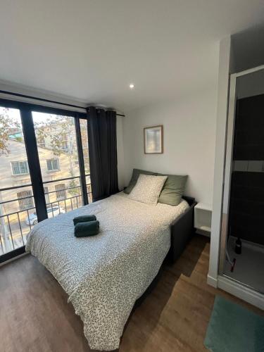 une chambre avec un lit et une grande fenêtre dans l'établissement L'Olivier - Joli duplex au cœur du centre ville à 2 pas de la Rotonde Mirabeau et des allées Provençales, à Aix-en-Provence