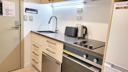 a small kitchen with a sink and a stove at Sky Stars Essential Reserve in Auckland