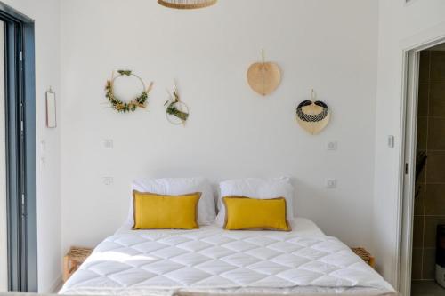 une chambre avec un lit blanc avec des oreillers jaunes dans l'établissement Marion - Agosta beach by foot Cozy - by TGB, à Albitreccia