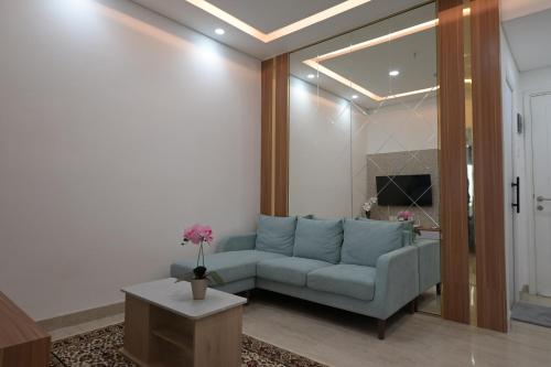a living room with a blue couch and a table at Apartment Medan Podomoro City Deli by OLS Studio in Medan