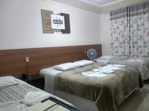 a hotel room with two beds and a window at Hotel Excelsior in Poços de Caldas