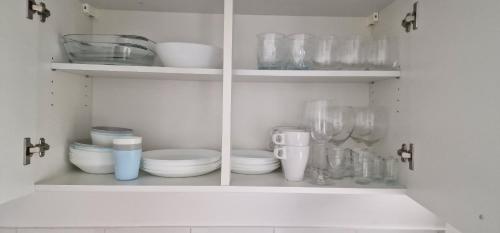 un armario blanco lleno de platos y vasos en Mb Homes Pfullingen 2, en Pfullingen