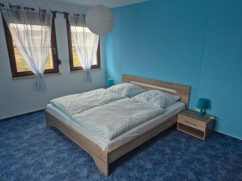 a bedroom with a bed in a blue room with two windows at Ferienwohnung Rochlitzer Berg Blick in Seelitz