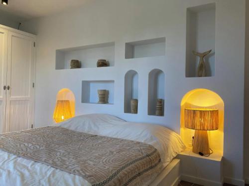 a bedroom with a bed with two lamps and shelves at Modern villa in Lajares with private pool in La Oliva