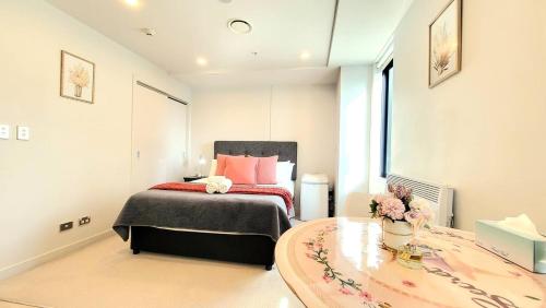 a bedroom with a bed and a table with flowers on it at Sky Stars Essential Reserve in Auckland