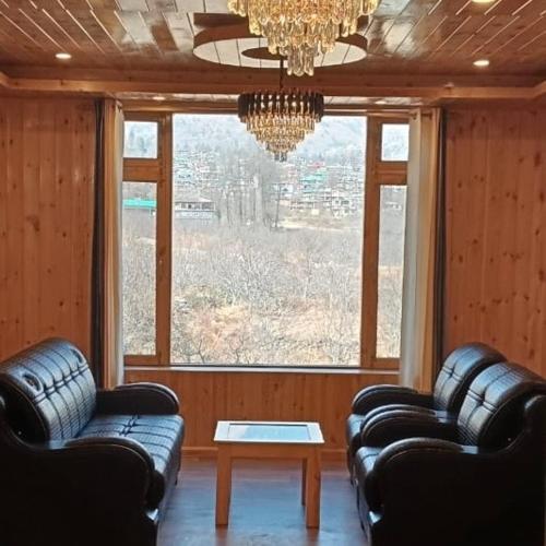 a living room with leather couches and a chandelier at Ekaant Stays - Manali in Manāli