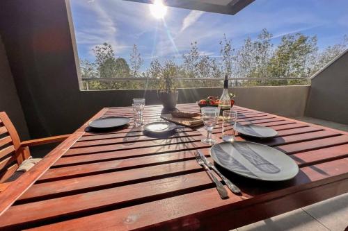 une table en bois avec des assiettes et des verres à vin dessus dans l'établissement Ornella - Terrace Wifi Cozy - by TGB, à Ajaccio