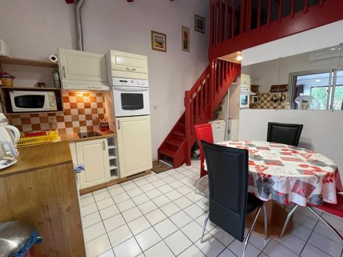 une cuisine avec une table et un escalier rouge dans l'établissement Maison 2 pièces mezzanine 6 couchages SC105-019, à Saint Cyprien Plage