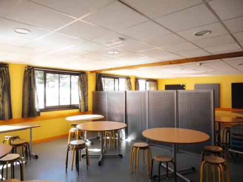 une salle de classe avec des tables et des chaises et des murs jaunes dans l'établissement Auberge de Jeunesse - Les Carlines I, à Vars