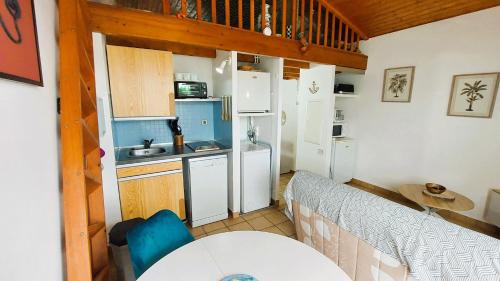 une petite cuisine avec des appareils électroménagers blancs et une table dans l'établissement Escale à la mer, plage de Royan à pied et balcon, à Saint-Georges-de-Didonne