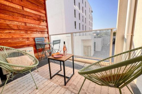 - une terrasse avec 2 chaises et une table avec une bouteille de vin dans l'établissement Gina - Modern Luminous Balcony - by TGB, à Ajaccio