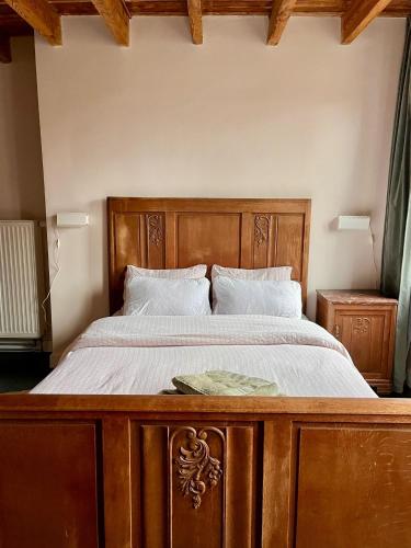 a bedroom with a wooden bed with white sheets at La Ronce Home in Écaussinnes-dʼEnghien