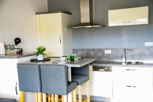 une cuisine avec des armoires blanches et un comptoir avec des tabourets dans l'établissement Francesca - Beach by foot Terrace - by TGB, à Porticcio