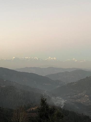 a view of snow covered mountains in the distance at EcoEscape Mukteshwar in Mukteswar