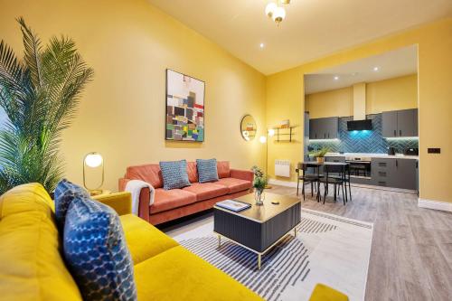 a living room with a yellow couch and a kitchen at Large Central Station 2 Bed Apartment A2 in Glasgow