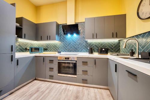 a kitchen with white cabinets and a clock on the wall at Large Central Station 2 Bed Apartment A2 in Glasgow