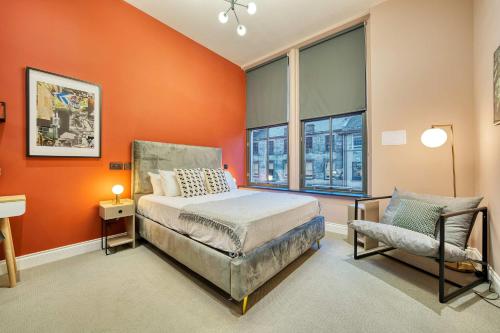a bedroom with orange walls and a bed and a chair at Large Central Station 2 Bed Apartment A2 in Glasgow