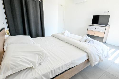 une chambre avec un lit avec des draps blancs et une télévision dans l'établissement Milla - Panoramic Terrace Calm & Cosy - by TGB, à Porticcio