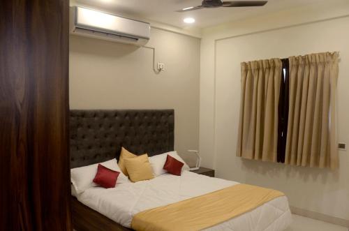 a bedroom with a bed with red and yellow pillows at Horizon Grande Apartments - Tarkarli in Malvan