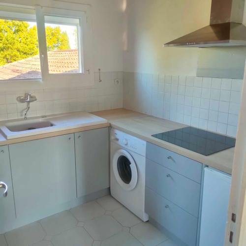une cuisine avec un évier et une machine à laver dans l'établissement Appartement avec grand jardin et parking, Uzès, à Uzès
