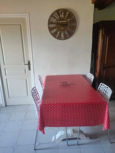 une table rouge avec des chaises et une horloge sur le mur dans l'établissement Appartement avec grand jardin et parking, Uzès, à Uzès