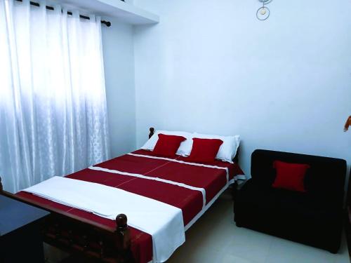 a bedroom with a red and white bed and a window at Alappuzha Family Vacation Villa - LAYANILA in Alleppey