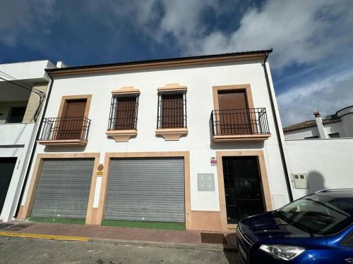 a white building with two garage doors on a street at El pasaje Apart in Ronda
