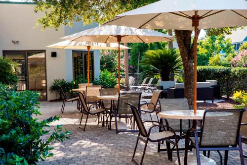 an outdoor patio with tables and chairs and umbrellas at Courtyard by Marriott Myrtle Beach Barefoot Landing in Myrtle Beach