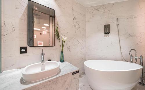 a white bathroom with a tub and a sink at Forestar Hotel in Seoul