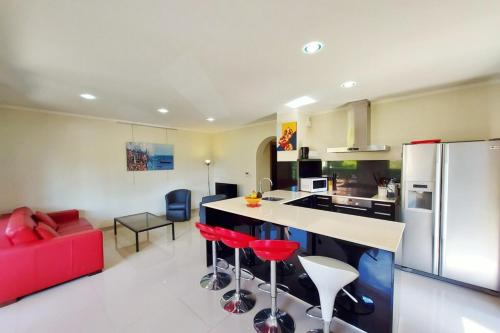 une cuisine avec tabourets de bar rouge et canapé rouge dans l'établissement Stella - Agosta beach by foot Terrace - by TGB, à Porticcio