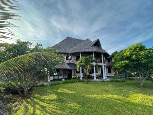 a house with a gambrel roof on a lawn at Colobus Suite of 40m2 in Villa 560 m2, View of the Indian Ocean in Shimoni