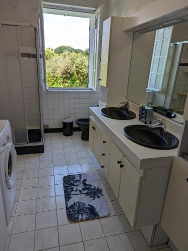 une salle de bain avec deux lavabos et une fenêtre dans l'établissement Maison indépendante calme et nature, à Pereyrols