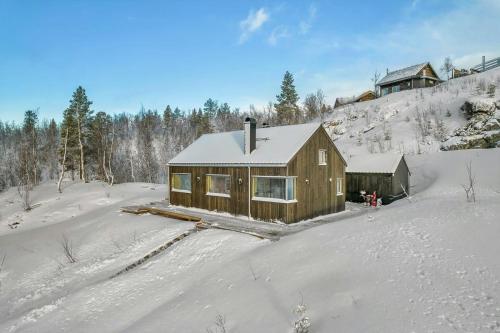 a log cabin in the snow with a house at Modern Cabin In Harmony With Nature in Moen i Målselv