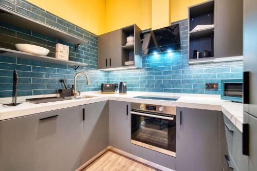 a kitchen with white counters and blue tiles at Stunning Central Station 2 Bed Apartment B4 in Glasgow