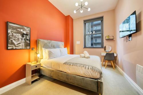a bedroom with orange walls and a bed and a window at Stunning Central Station 2 Bed Apartment B4 in Glasgow