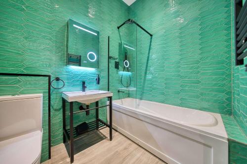 a green tiled bathroom with a tub and a sink at Stunning Central Station 2 Bed Apartment B4 in Glasgow