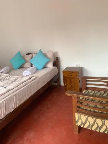 a bedroom with a bed with blue pillows and a chair at Broad view in Ella