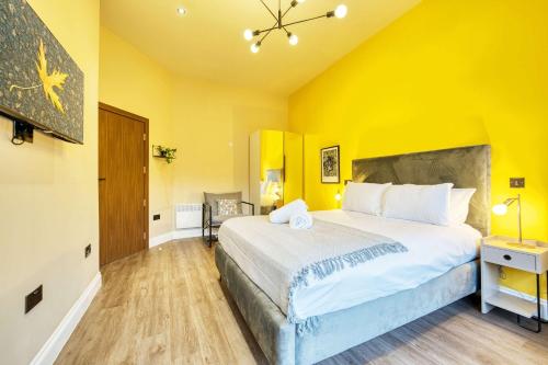 a bedroom with a large bed and a yellow wall at Lovely Central Station 1 Bed Apartment A6 in Glasgow