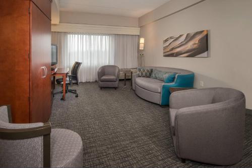 a hotel room with a couch and chairs and a television at Courtyard by Marriott Hagerstown in Hagerstown