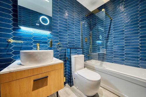 a blue tiled bathroom with a toilet and a sink at Lovely Central Station 1 Bed Apartment A6 in Glasgow