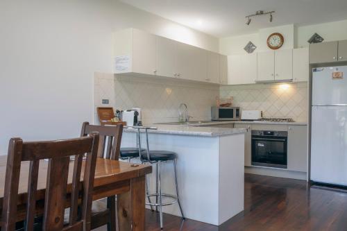 a kitchen with white appliances and a table and chairs at Halls Gap Escape Townhouses in Halls Gap