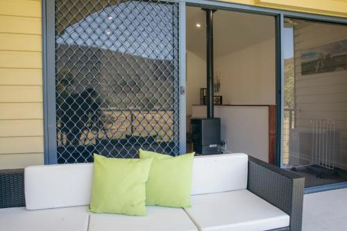a white couch with two yellow pillows on a patio at Halls Gap Escape Townhouses in Halls Gap