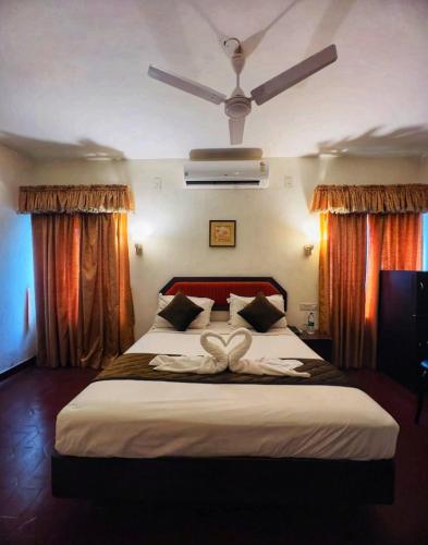 a bedroom with a large white bed with curtains at Mangotree Kochi in Cochin