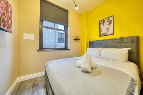 a bedroom with a bed with yellow walls and a window at Lovely Central Station 1 Bed Apartment B10 in Glasgow