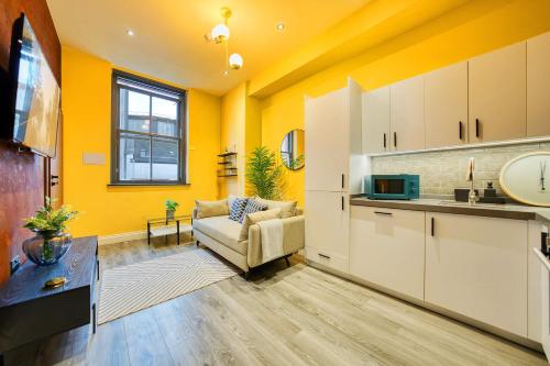 a living room with yellow walls and a couch and a kitchen at Smart Central Station 1 Bed Apartment B11 in Glasgow
