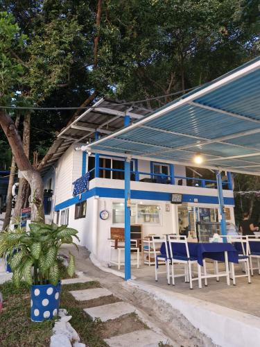 a blue and white building with tables and chairs at Secret Garden Family House in Ko Chang