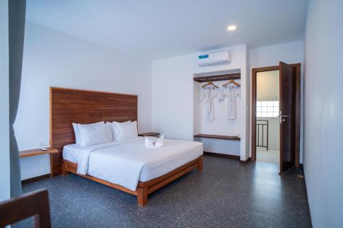 a bedroom with a white bed with a wooden headboard at Apartment Collection in Phum Pobos