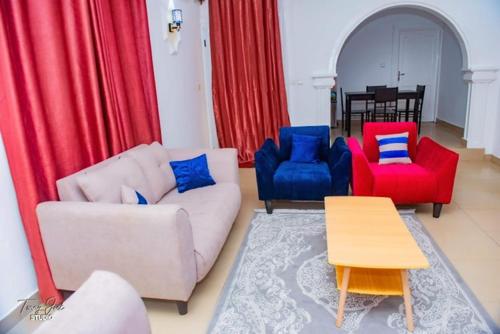 a living room with red and blue chairs and a table at Villa MBOLO in Pointe-Noire