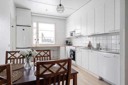 a kitchen with white cabinets and a table with chairs at Lakefront 2BR Home with Sauna near Railway Station & Downtown in Jyväskylä