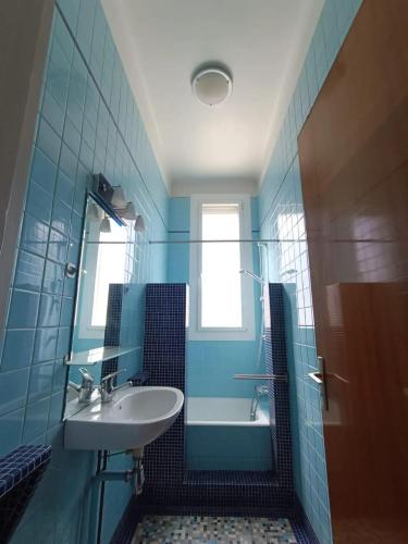 La salle de bains bleue est pourvue d'un lavabo et d'une baignoire. dans l'établissement Appartement spacieux à Montreuil, terrasse agréable, 150 m², à Montreuil